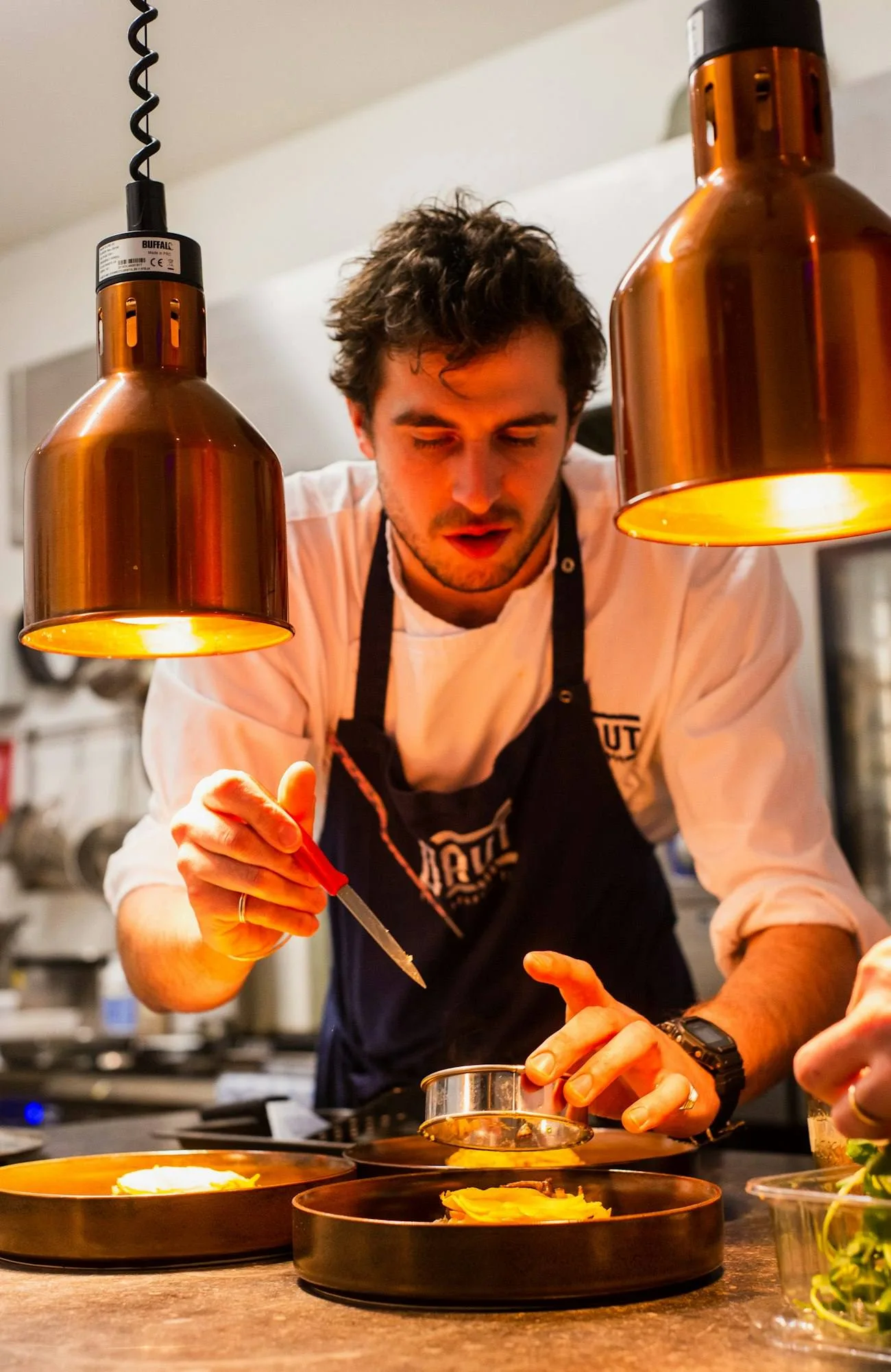 Julien Casal en cuisine sous les lampes de cuivre