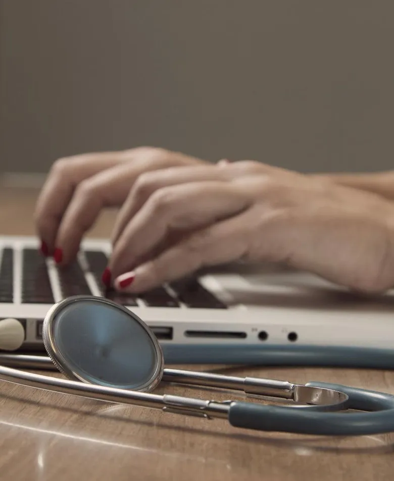 Ordinateur portable et stéthoscope sur un bureau.