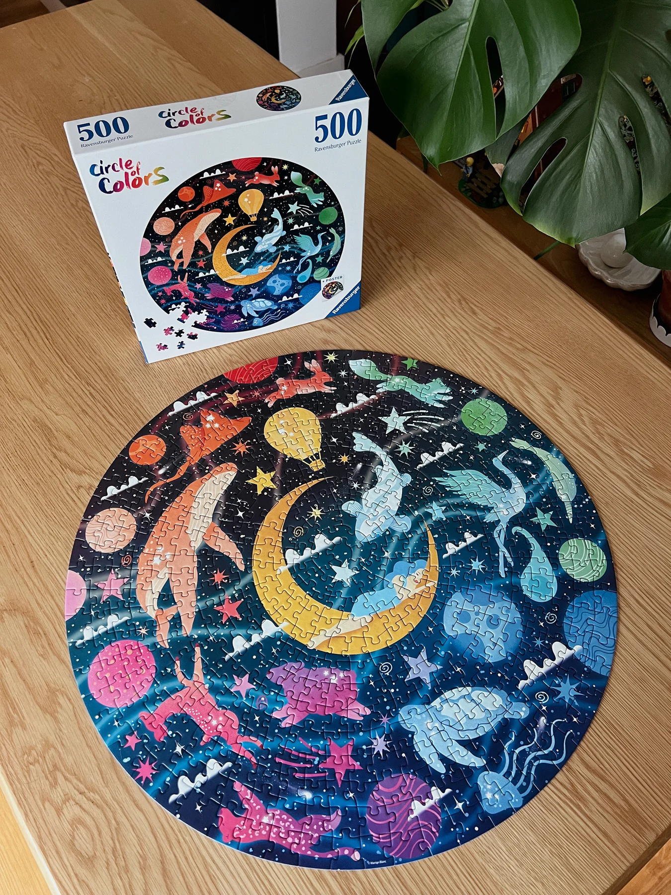 Puzzle rond Rêves assemblé sur une table à côté de sa boîte Ravensburger